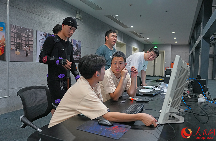 崔晟輯（前排右二）和團(tuán)隊(duì)成員在動(dòng)作捕捉棚內(nèi)討論設(shè)計(jì)方案。 人民網(wǎng)記者 崔新耀攝